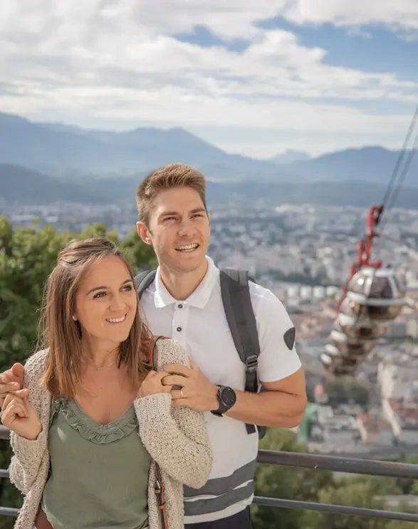 Un couple de jeunes randonneurs sourient en haut de la montagne surplombant Grenoble